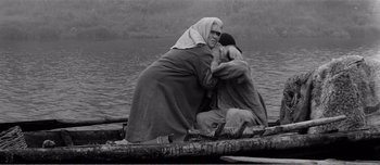 Movie still from “Andrei Rublev” (1966), directed by Andrei Tarkovsky – Two people in a boat on a body of water; Medium shot, High angle