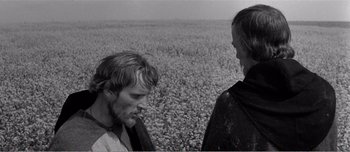 Movie still from “Andrei Rublev” (1966), directed by Andrei Tarkovsky – Two people standing next to each other in a field; Medium shot, Over the shoulder angle