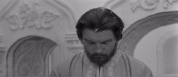 Movie still from “Andrei Rublev” (1966), directed by Andrei Tarkovsky – A man with long hair and a beard is looking down; Close Up shot, Low angle
