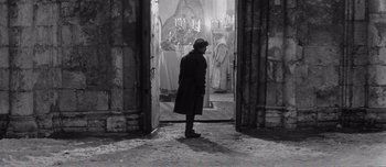 Movie still from “Andrei Rublev” (1966), directed by Andrei Tarkovsky – A man standing in front of an open door; Wide shot, High angle