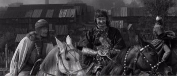 Movie still from “Andrei Rublev” (1966), directed by Andrei Tarkovsky – A man in a costume riding on a horse; Medium shot, High angle