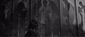 A woman standing in front of an image of jesus
