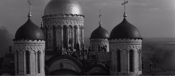 Movie still from “Andrei Rublev” (1966), directed by Andrei Tarkovsky – A black and white photo of a church with workers working on it; Extreme Wide shot, High angle
