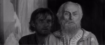 Movie still from “Andrei Rublev” (1966), directed by Andrei Tarkovsky – A man standing next to an older man in front of a window; Close Up shot, Over the shoulder angle