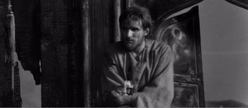 Movie still from “Andrei Rublev” (1966), directed by Andrei Tarkovsky – Black and white photograph of a man in a shirt; Medium shot, High angle