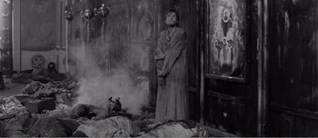 Movie still from “Andrei Rublev” (1966), directed by Andrei Tarkovsky – A man standing in the middle of a room with smoke coming out of the floor; Wide shot, High angle