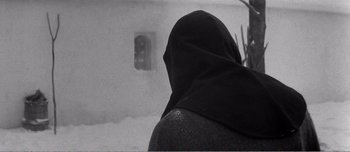 Movie still from “Andrei Rublev” (1966), directed by Andrei Tarkovsky – A person with a black head covering in the snow; Close Up shot, Low angle