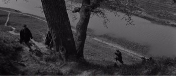 Movie still from “Andrei Rublev” (1966), directed by Andrei Tarkovsky – A black and white photo of a person running near a tree; Extreme Wide shot, High angle