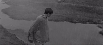Movie still from “Andrei Rublev” (1966), directed by Andrei Tarkovsky – A man walking in the rain near a body of water; Wide shot, High angle