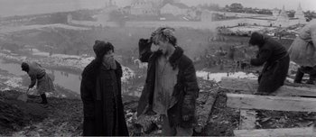 Movie still from “Andrei Rublev” (1966), directed by Andrei Tarkovsky – Two people standing on top of a hill near a city; Medium shot, Over the shoulder angle