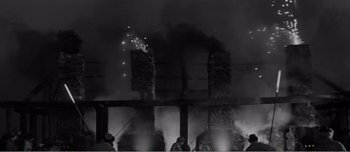 A black and white photo of people standing in front of a fire
