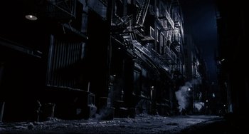 A dark city street with fire escapes lit up at night