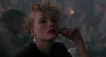 Movie still from “Angel Heart” (1987), directed by Alan Parker – A woman with a curly hair and red lipstick is holding her hand to her face; Close Up shot, Over the shoulder angle