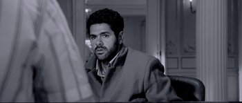 Movie still from “Angel-A” (2005), directed by Luc Besson – A black and white photo of a man looking at the camera; Close Up shot, Over the shoulder angle