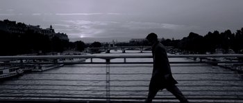 Movie still from “Angel-A” (2005), directed by Luc Besson – A man walking on a bridge over a body of water; Wide shot, Low angle