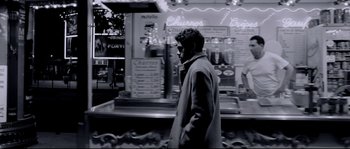 Movie still from “Angel-A” (2005), directed by Luc Besson – A black and white photo of a man walking down the street; Medium shot, Low angle