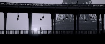 Movie still from “Angel-A” (2005), directed by Luc Besson – A person walking on a bridge near the eiffel tower; Extreme Wide shot, Low angle