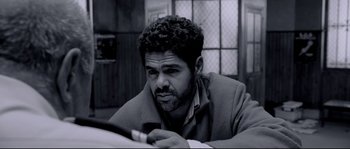 Movie still from “Angel-A” (2005), directed by Luc Besson – Black and white photograph of a man looking at his cell phone; Close Up shot, High angle