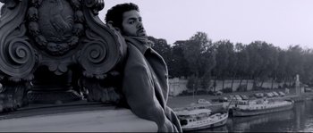 Movie still from “Angel-A” (2005), directed by Luc Besson – A black and white photo of a man leaning against a wall; Medium shot, Low angle