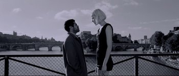Movie still from “Angel-A” (2005), directed by Luc Besson – A man and a woman standing next to each other on a bridge; Medium shot, Low angle