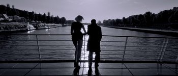 Movie still from “Angel-A” (2005), directed by Luc Besson – A man and a woman standing next to each other on a bridge; Wide shot, Low angle