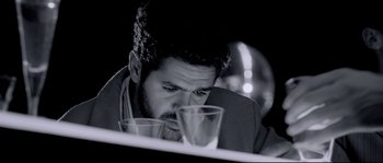 Movie still from “Angel-A” (2005), directed by Luc Besson – A black and white photo of a man looking down at a glass; Close Up shot, Low angle