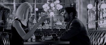 Movie still from “Angel-A” (2005), directed by Luc Besson – A man and a woman sitting at a table in front of a chandelier; Medium shot, Over the shoulder angle