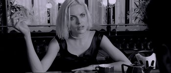 Movie still from “Angel-A” (2005), directed by Luc Besson – A woman sitting at a table with a cup of coffee in front of her; Close Up shot, Over the shoulder angle