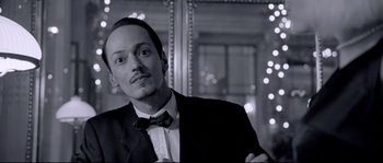 Movie still from “Angel-A” (2005), directed by Luc Besson – A black and white photo of a man in a suit and bow tie; Close Up shot, Low angle