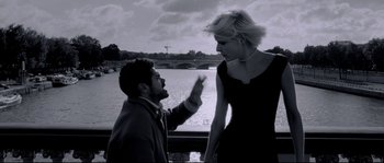 Movie still from “Angel-A” (2005), directed by Luc Besson – A man and a woman standing next to a body of water; Medium shot, Low angle