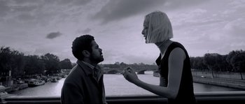 Movie still from “Angel-A” (2005), directed by Luc Besson – A man and a woman standing next to a body of water; Medium shot, Low angle