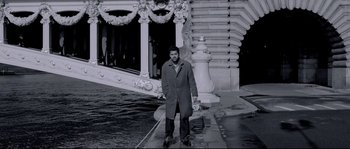 Movie still from “Angel-A” (2005), directed by Luc Besson – A black and white photo of a man standing on the sidewalk; Wide shot, High angle