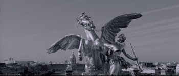 Movie still from “Angel-A” (2005), directed by Luc Besson – A large statue of a winged horse and a statue of a woman; Wide shot, Low angle