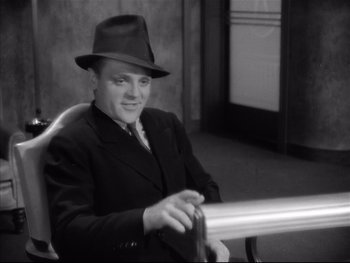 Movie still from “Angels with Dirty Faces” (1938), directed by Michael Curtiz – A man in a suit and a hat sitting in a chair; Medium shot, High angle