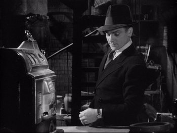 Movie still from “Angels with Dirty Faces” (1938), directed by Michael Curtiz – A black and white photo of a man in a suit and hat; Medium shot, Low angle