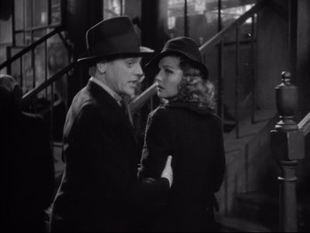 Movie still from “Angels with Dirty Faces” (1938), directed by Michael Curtiz – A man and a woman standing next to each other in front of stairs; Medium shot, Low angle