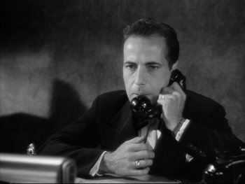 Movie still from “Angels with Dirty Faces” (1938), directed by Michael Curtiz – A black and white photo of a man talking on a phone; Close Up shot, High angle