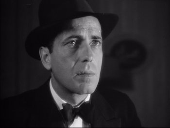 Movie still from “Angels with Dirty Faces” (1938), directed by Michael Curtiz – A black and white photo of a man wearing a hat and a bow tie; Close Up shot, Low angle