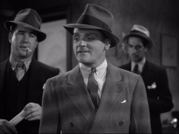 Movie still from “Angels with Dirty Faces” (1938), directed by Michael Curtiz – A black and white photo of a man in a suit and hat; Medium shot, Low angle