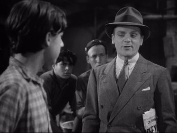 Movie still from “Angels with Dirty Faces” (1938), directed by Michael Curtiz – A man in a suit and a hat talking to some people; Medium shot, Low angle