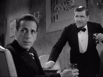 Movie still from “Angels with Dirty Faces” (1938), directed by Michael Curtiz – Two men in suits and one is holding a glass; Medium shot, Over the shoulder angle