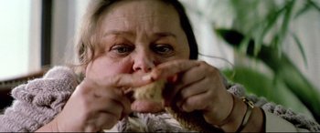 Movie still from “Anguish” (1987), directed by Bigas Luna – An older woman eating a piece of bread; Extreme Close Up shot, Overhead angle
