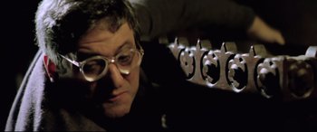 Movie still from “Anguish” (1987), directed by Bigas Luna – A man wearing glasses looking at the camera; Close Up shot, Low angle