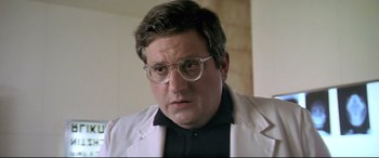 Movie still from “Anguish” (1987), directed by Bigas Luna – A person wearing glasses and a lab coat; Close Up shot, Low angle