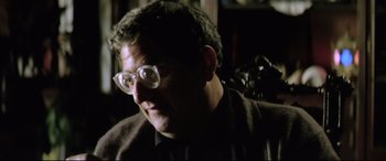 Movie still from “Anguish” (1987), directed by Bigas Luna – A person wearing glasses; Close Up shot, Over the shoulder angle