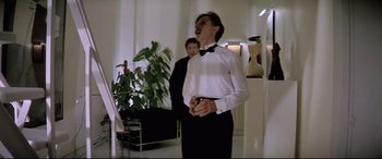 Movie still from “Anguish” (1987), directed by Bigas Luna – A man in a bow tie is holding a microphone; Medium shot, Low angle