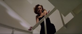 Movie still from “Anguish” (1987), directed by Bigas Luna – A woman in a black dress standing on top of a white railing; Medium shot, Low angle