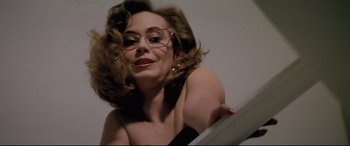 Movie still from “Anguish” (1987), directed by Bigas Luna – A woman with glasses looking into a mirror; Close Up shot, Low angle