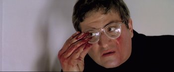 Movie still from “Anguish” (1987), directed by Bigas Luna – A man with blood on his face holding a pair of eye glasses; Close Up shot, Low angle