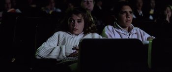 Movie still from “Anguish” (1987), directed by Bigas Luna – A little girl sitting in front of a projector screen; Medium shot, Low angle